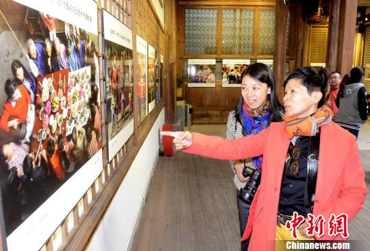 展廳內，由臺灣女攝影家楊欣參展的作品《團圓飯》前，臺灣農村美國際觀光發展協會理事長、鄧南光影像紀念館館長黃翠文(右)饒有興致地向觀眾講述，該作品的創作經過及照片背後的故事。　記者劉可耕 攝