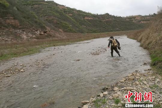 圖為童金南教授趟水過河前往剖面。　田力 攝