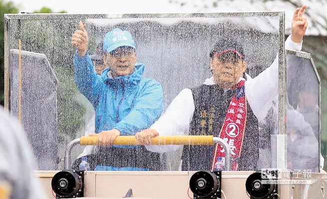 國民黨候選人朱立倫（左）6日陪同“立委”候選人張慶忠（右）以車隊冒雨掃街，透過防彈宣傳車隱約呈現兩人輪廓