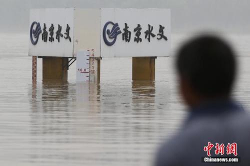 資料圖：7月6日，一位市民在長江南京下關水文尺規前經過。當日，南京水文局發佈的資訊顯示，長江水位上漲迅速，最高峰達9.8米，持續超過警戒線。中新社記者 泱波 攝