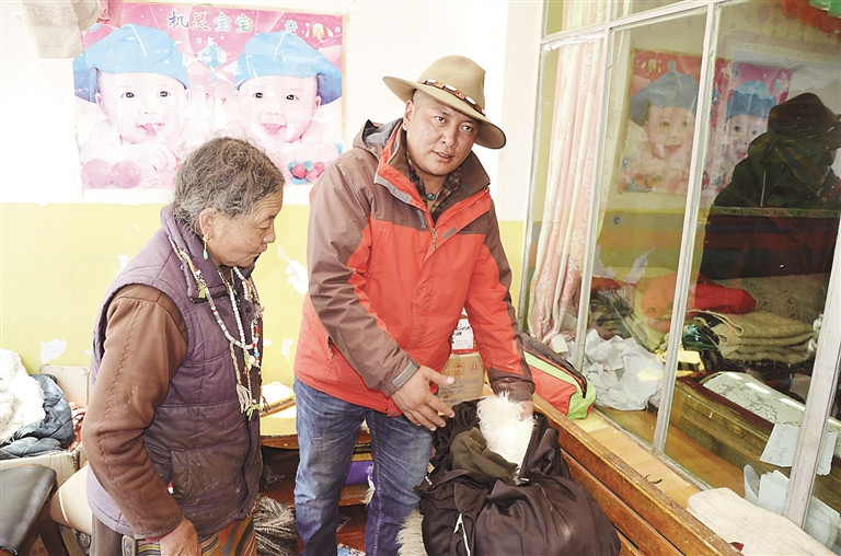 圖為嘎措鄉鄉長羅布佔堆正在檢查製作羊毛毯的原材料品質。