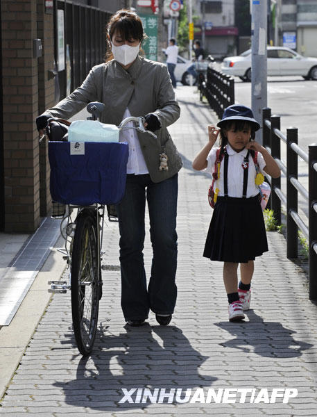 5月18日，在日本大阪市，一名小學生在學校停課後被媽媽接回家。日本大阪府和兵庫縣的非輸入性甲型H1N1流感確診病例近兩天已從“零”飆升至120多例。為了遏制疫情蔓延，上述兩地的政府部門已于18日先後要求總計1400多所教育機構暫時停課。