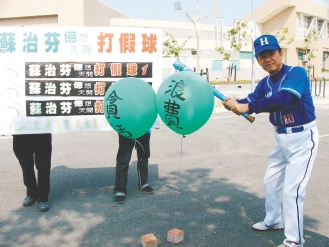 吳威志舉起球棒，作勢打擊寫有“貪污”和“浪費”的汽球。《聯合報》圖片