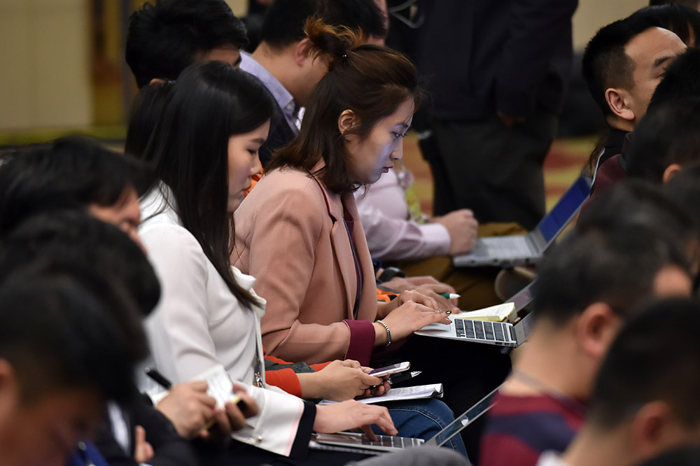 3月7日，在記者會上，女記者在爭分奪秒編發稿件。