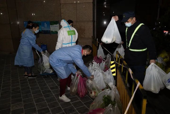 3月31日，在上海市中遠兩灣城小區，社區和街道幹部為封控樓棟居民送菜。新華社記者金立旺攝