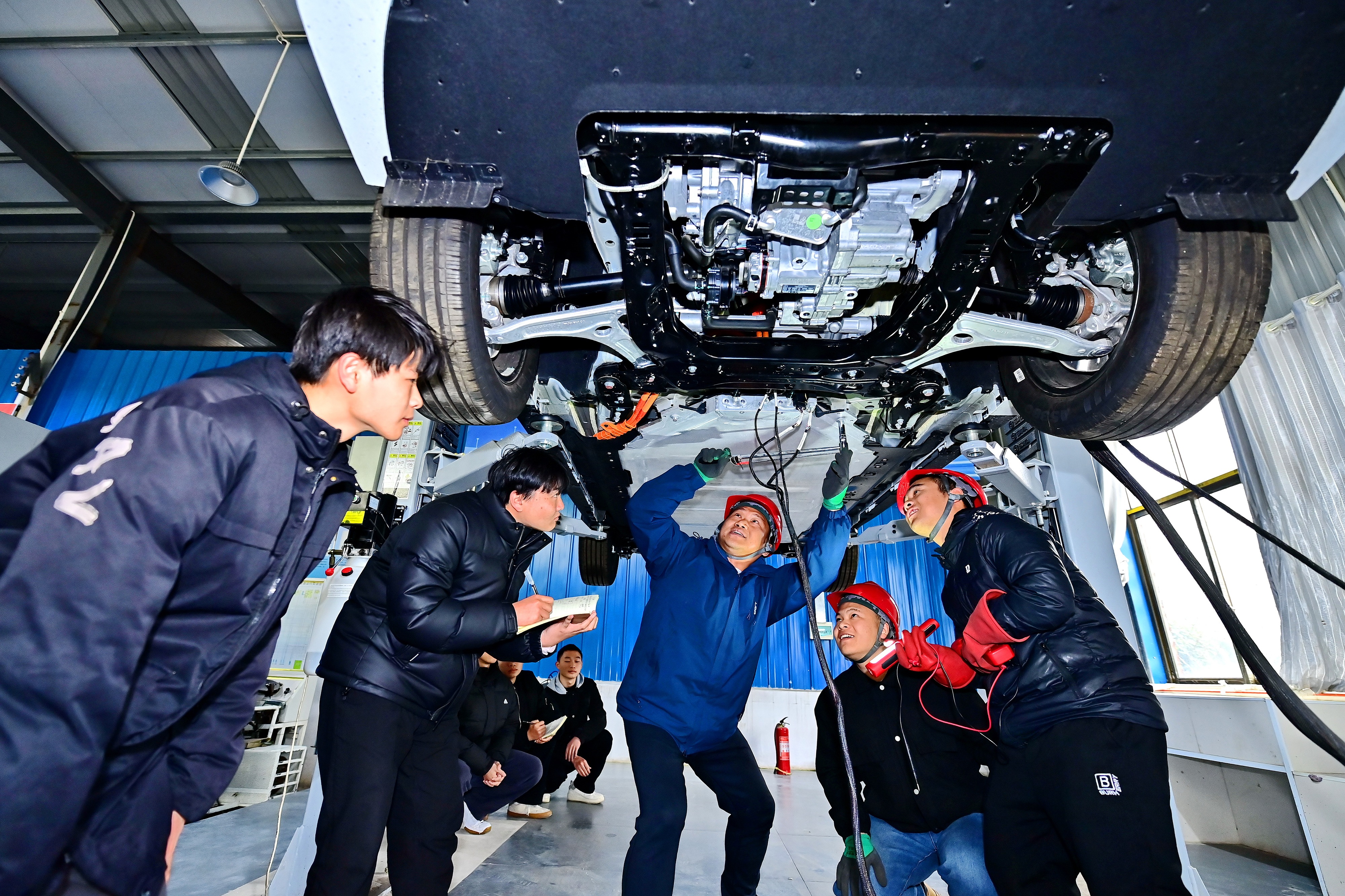 2025年2月17日，江西省宜春市，豐城市的一所技工學校實訓基地內，新能源汽車運維專業學生在老師的指導下學習新能源汽車電池包檢修技術。